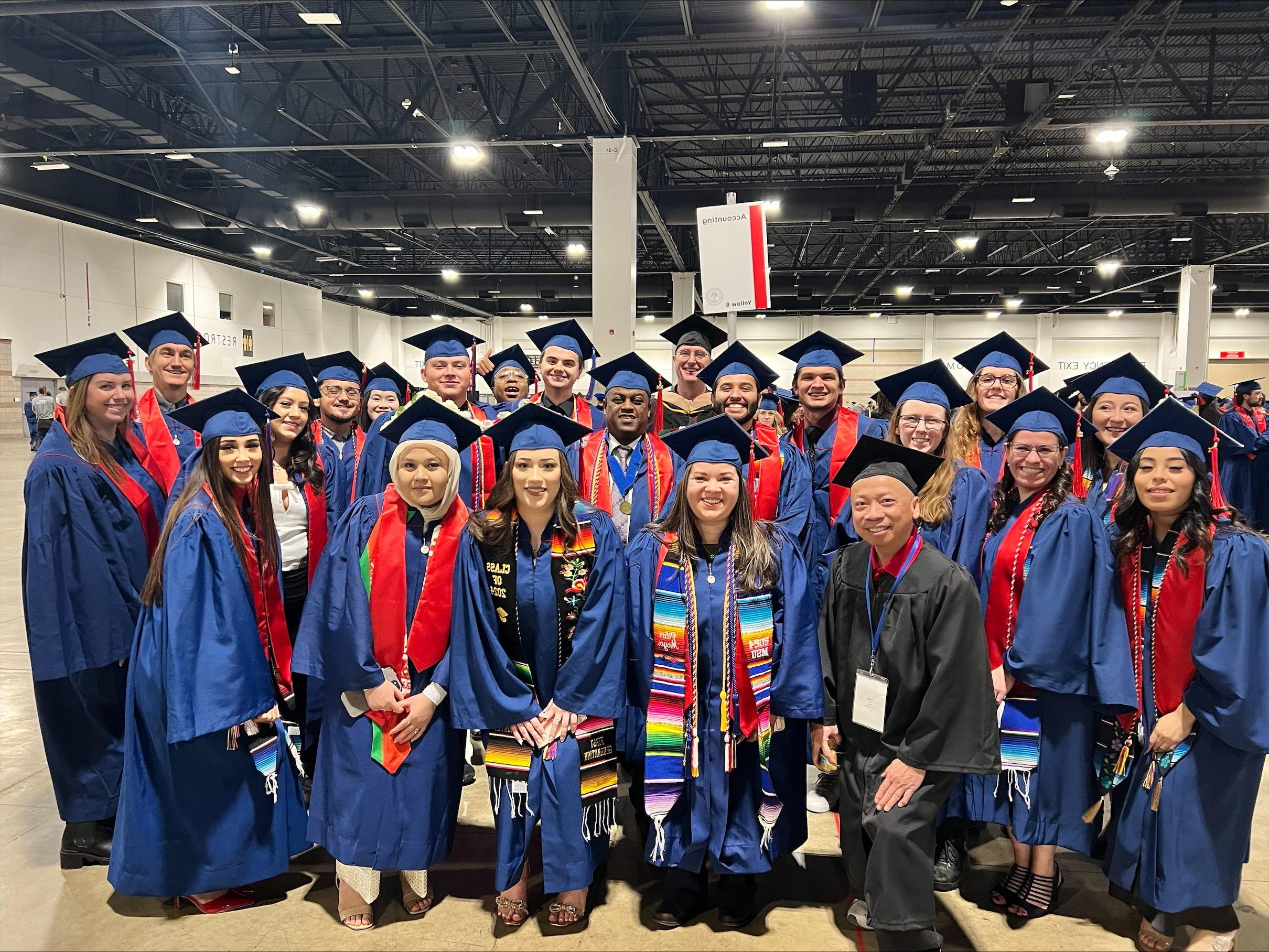 accounting group grads in regalia smiling at fall '24 commencement in assembly area